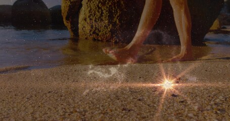 Naklejka premium Stepping bare feet on wet pebbly shoreline by mossy rocks with starburst reflection, copy space