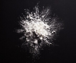 White flour powder explosion on black background