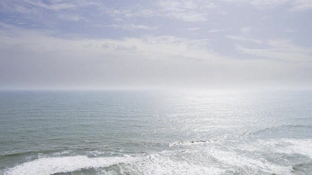 aerial drone shot flying back over stormy sea to golden beach and pine coconut tree covered coastline at Kappil bekal beach popular tourist spot
