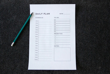 blank daily plan' sheet with a pencil next to it isolated on dark background, daily planning concept, habits, daily routine