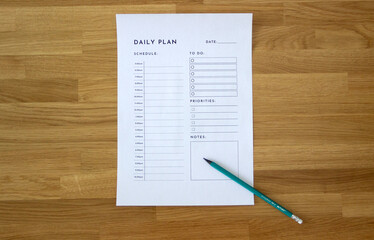 blank sheet titled 'Daily Plan' on a wooden table, with a pencil pointing at it, daily planning concept, habits, tasks, daily routine, lifestyle