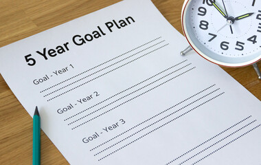 close-up of a sheet that says '5 year goal plan' with an alarm clock and a pencil next to it, blank