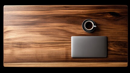 A minimalist flat lay showcases a closed laptop and a dark coffee cup resting on a richly textured walnut wood surface, evoking a sense of calm productivity and modern simplicity.