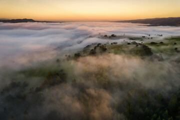 Aerial view of a mountain landscape shrouded in morning fog during golden hour
