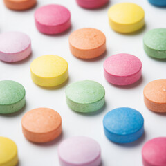 Colorful round tablets arranged in rows on white background