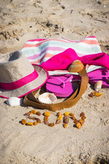 Inscription sun made of amber and accessories for relax on sand. Straw hat, slippers and towel. Vacation time on beach