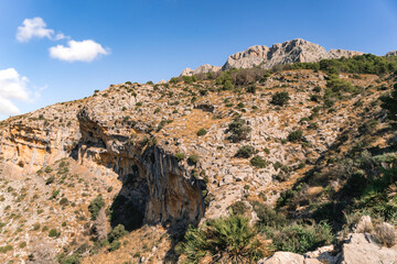 Fototapeta premium View of the Sierra de Bernia mountain range and trail, Costa Blanca, Alicante, Spain. Dramatic limestone ridges rising above the Mediterranean landscape.