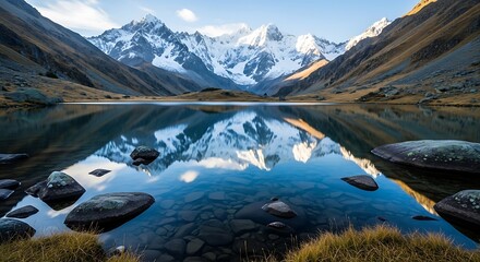 A serene mountain lake reflects a snow-capped mountain range under a partly cloudy sky, rocks dot the foreground
