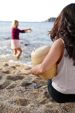 Mother and daughter scattering ashes by the sea