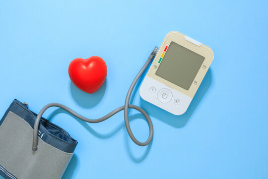Blood pressure monitor and heart on blue background