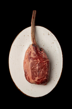 Raw tomahawk steak on a plate for gourmet cooking