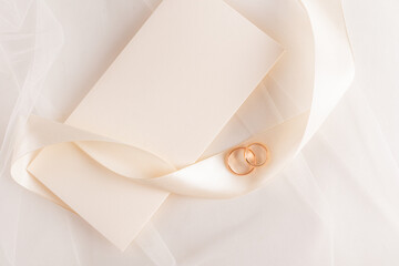 Wedding rings and envelope on soft tulle background