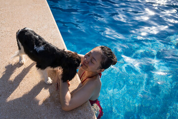 Woman enjoying a swim with her dog at the poolside