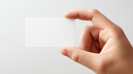 Obraz premium Hand Holding Blank White Card Mockup for Design Presentation on a Plain Background