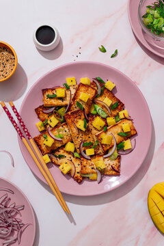 Top view of fried tofu with mango and vibrant garnishes