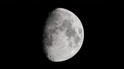 Obraz premium Close up view of a half moon against a black night sky, showing detailed surface craters and texture.