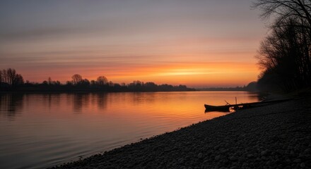 Obraz premium Serene sunset over a calm river with a lone boat and vibrant sky reflections.