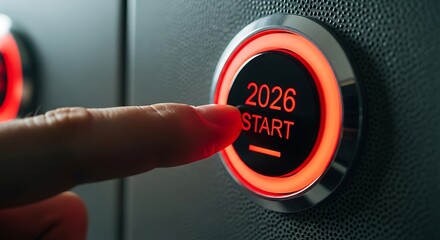 Close-up of finger pressing illuminated red start button with year 2026 on textured surface
