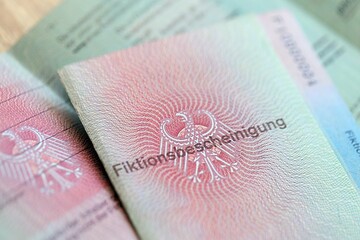 Obraz premium German temporary Permanent resident card lies on wooden table. Fiktionsbescheinigung