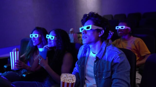 Young people enjoying a 3d film at the cinema, eating popcorn and wearing 3d glasses, slow motion montage effect