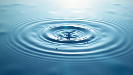 Water droplet splash with concentric ripples on calm surface.  
