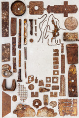 A group of various old rusty bits and pieces arranged on a concrete surface. Old rusty nuts, bolts, nails and other parts flay lay on gray background.
