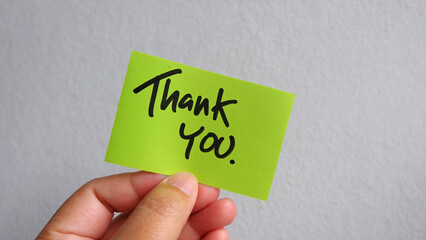 Hand holding thank you,  sticky note on white background.