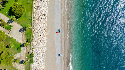 Aerial drone view of hotel resort houses on sandy beach with turquoise sea waves, people sunbathing, swimming and relaxing on holiday vacation, Antalya Konyaalti beach, Turkey