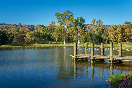 A serene landscape of an urban park with a pond and boat dock located at Carbon Canyon Regional Park in  Brea, California.