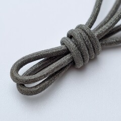 Close up abstract shot of a thick grey rope tied in a knot against a plain light background