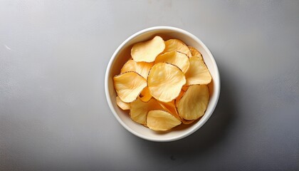 bowl of crispy organic cassava chips in a white ceramic bowl centered on a textured gray background with ample copy space around the bowl