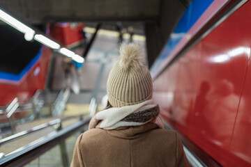 Woman going up on escalator in subway station during christmas season