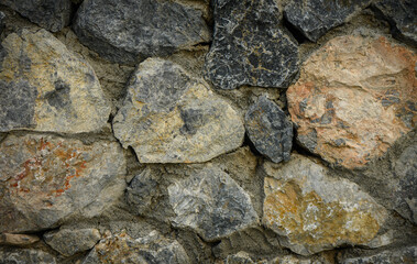 Macro view of a textured stone wall with sun rays creating shadows and highlights. Ideal for architecture, outdoor, or design projects.