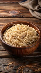 Close-up of a serving of raw brown rice noodles in a shallow bowl on a rustic wooden table