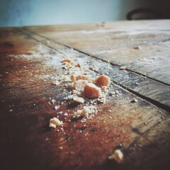 Close up of a textured natural cellulose sponge resting on a rustic wooden cutting board with a grey textured background