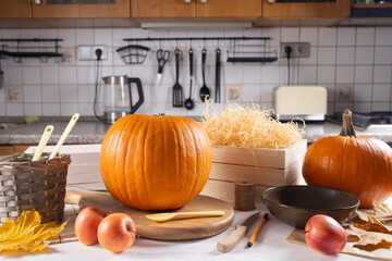 Vibrant orange pumpkins and fresh apples arranged on a kitchen countertop, surrounded by cooking...