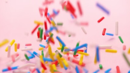 colorful cascade of sprinkles flows in slow motion, set against serene pink background, offering playful touch to any creative project, super slow motion - Powered by Adobe