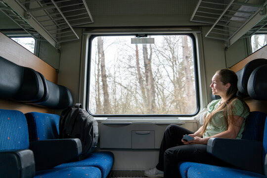 Mujer feliz y sonriente mirando por la ventana durante su viaje en tren