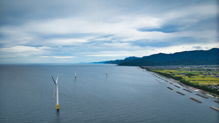 雨が降りそうな9月の富山県入善町沿岸からみる洋上風力発電風車をはじめとする様々なもの