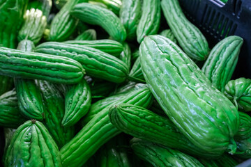 The image features a tightly packed pile of green bitter melons