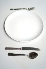Ceramic white plate with spoon, fork, knife