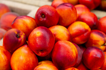 Pyramid of clean fresh nectarines on the counter in a basket. Juicy summer fruits for sale