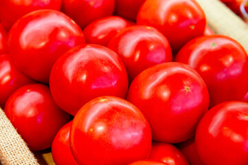 Red tomatoes are lying in transparent trays on the shop counter. Tomato theme background