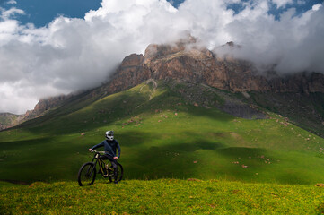 Young sportsman standing in a field with a bicycle. Man with a bicycle on top of a hill at noon....