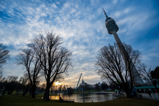 Olympiapark M&uuml;nchen bei Sonnenuntergang mit See, Schw&auml;nen und ikonischer Zeltdacharchitektur