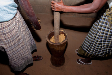 Close-Up of Women Pounding Crops to Make Traditional Flour in a Large African Wooden Mortar