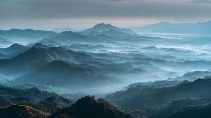 Majestic layers of a blue mountain range fading into the horizon through a serene sea of clouds and mist at dawn