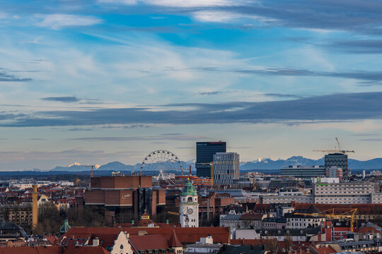 Blick &uuml;ber M&uuml;nchen auf das Riesenrad im Werksviertel und die schneebedeckten Alpen bei Sonnenuntergang