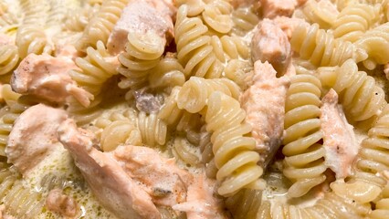 Spiraling fusilli entwined with succulent salmon, evoking maritime festivity and Nordic culinary delight, celebrates the ocean's bounty