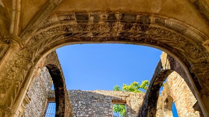 Arched ruins bask under cerulean sky, echoing medieval whispers and capturing Midsummer's Day solstice, ethereal architecture in sunlit harmony